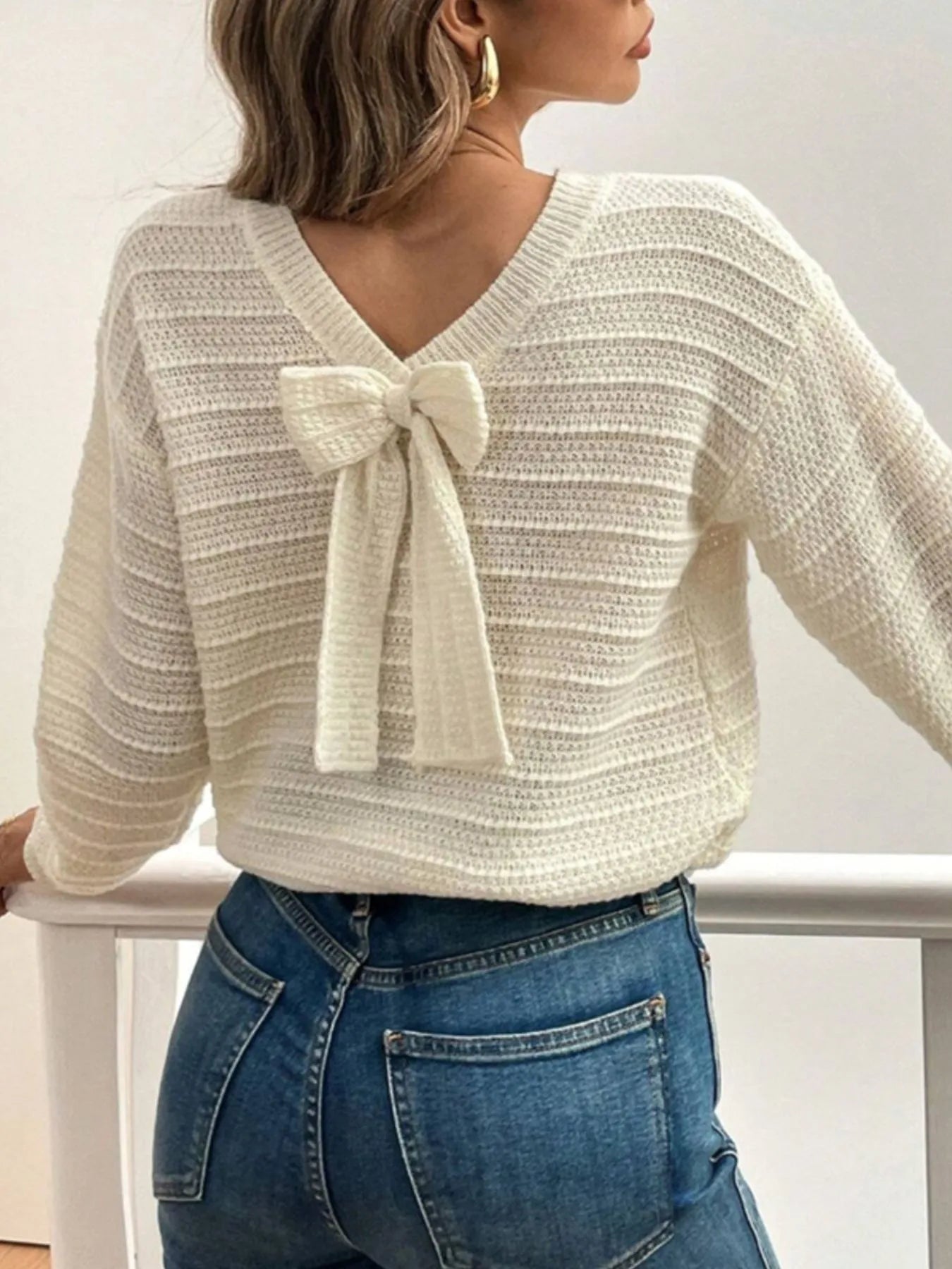 Trendsi Bow-Back Knit Top cream textured V back sweater with bow tie detail worn with blue jeans