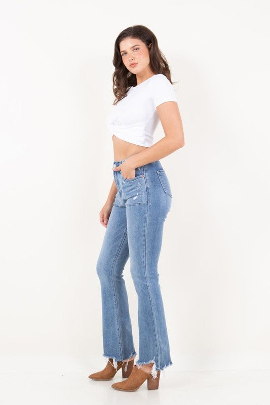 Artemis Vintage model wearing women's high rise tummy control jeans in light wash with flared legs and raw hem