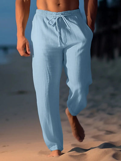 Light blue drawstring wide leg pants worn by a man walking barefoot on the beach