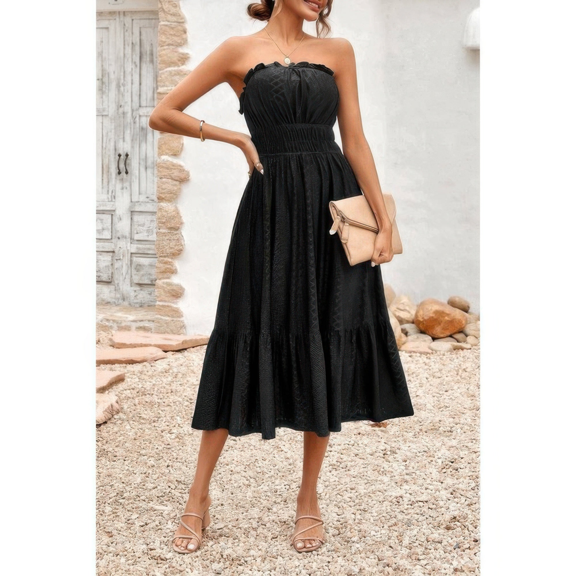 Woman wearing black strapless Elasit Waist Ruffle Dress with smocked elastic waist ruffle hem clutch and strappy sandals