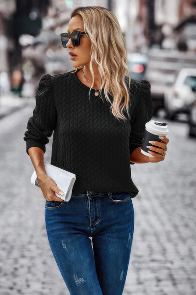 Loose Fit Pullover black cable knit sweater with puff shoulders worn by woman with coffee and clutch