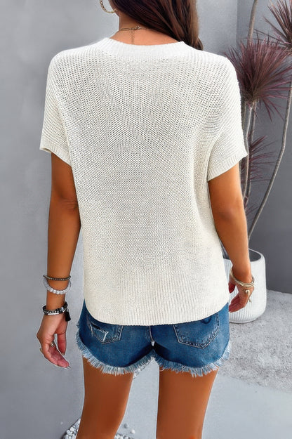 Back view of woman wearing a white ribbed knit loose top with short sleeves and denim cutoff shorts