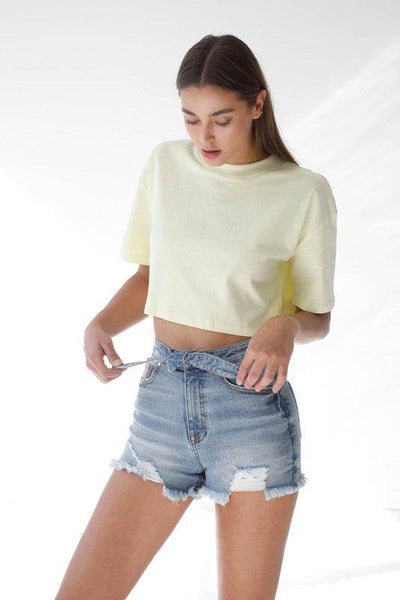 Casual model wearing High Waisted Denim Shorts with a light yellow cropped shirt for summer style