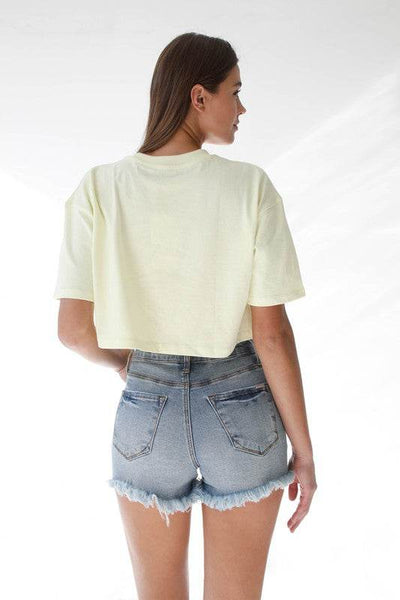 Back view of a model wearing High Waisted Denim Shorts paired with a cropped yellow t-shirt
