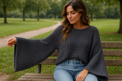 Woman in openwork batwing sweater sitting on park bench showing openwork pattern