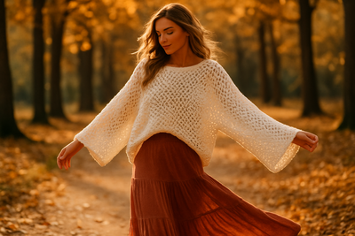 Woman in openwork batwing sweater walking through autumn park