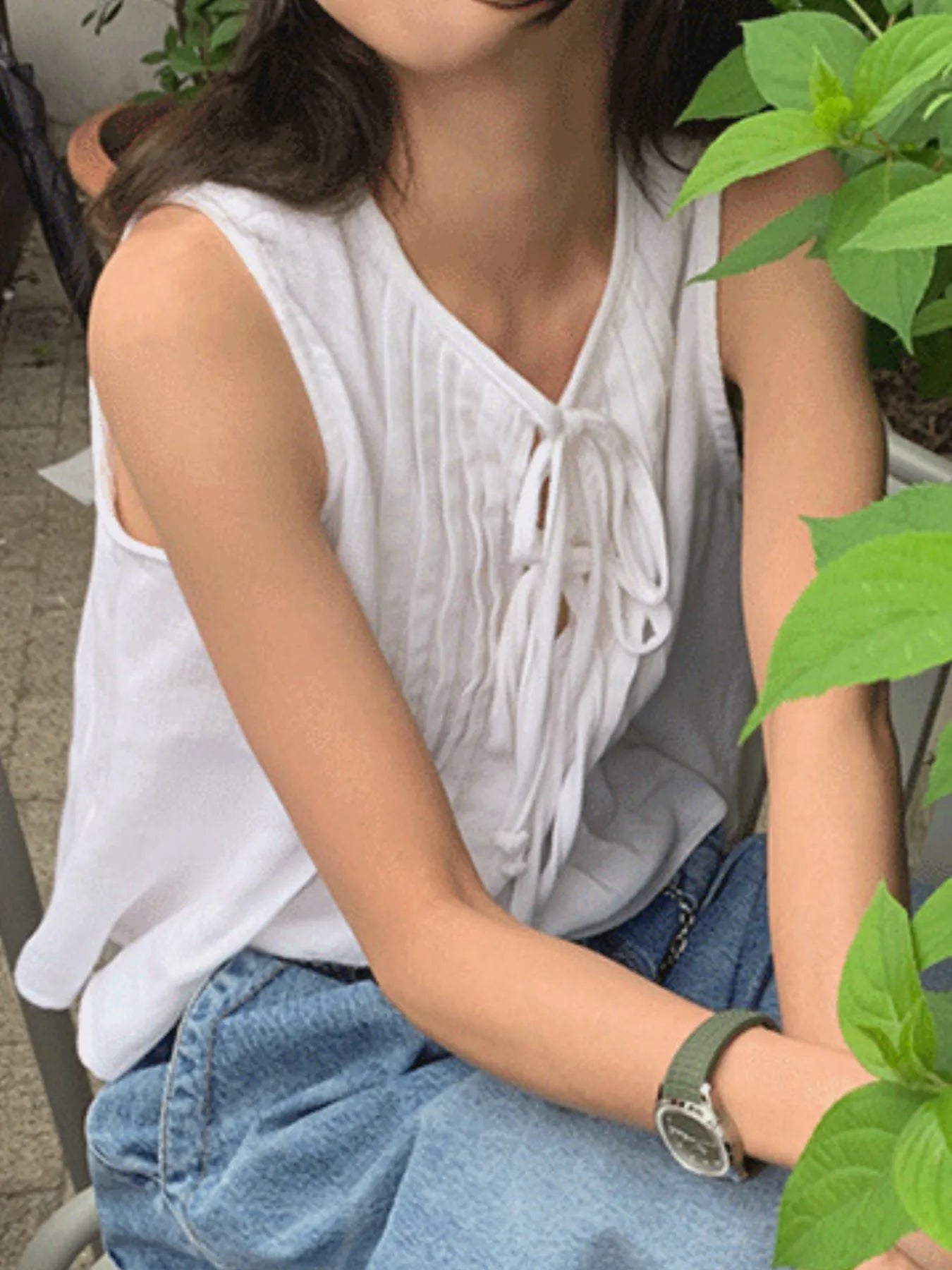 Trendsi white Sleeveless Summer Blouse with pintuck front and tie detail paired with blue jeans outdoors
