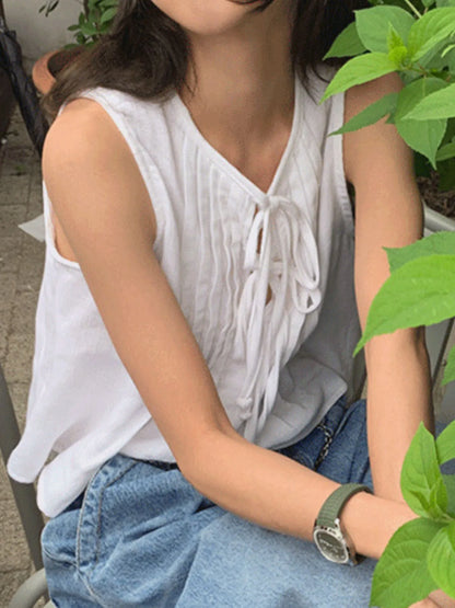 Trendsi white Sleeveless Summer Blouse with pintuck front and tie detail paired with blue jeans outdoors