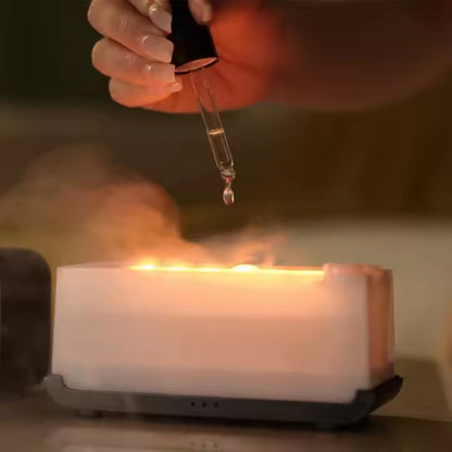 Fashions Envy Flame Aromatherapy Humidifier glowing with warm flame effect and mist as hand adds oil