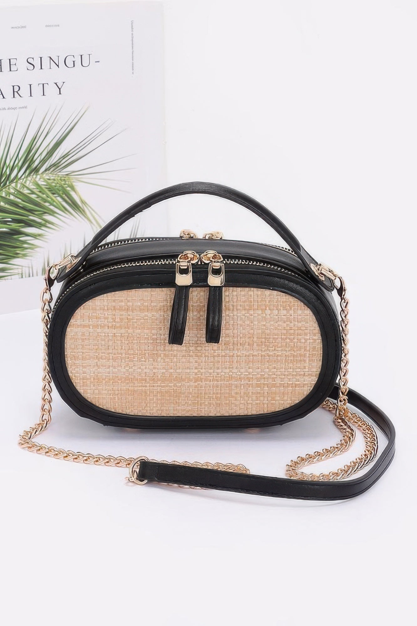 Small neutral faux straw bowling bag with black trim gold chain crossbody strap and top handle