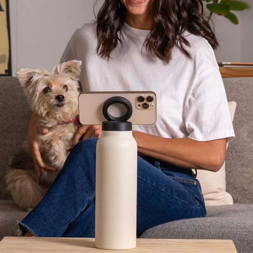 Fashions Envy Magnetic Phone Holder on a travel water bottle holding smartphone horizontally beside woman with dog