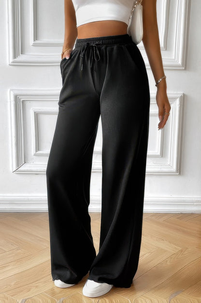 Model wearing black women's elastic waist straight pants with drawstring pockets paired with white crop top and sneakers
