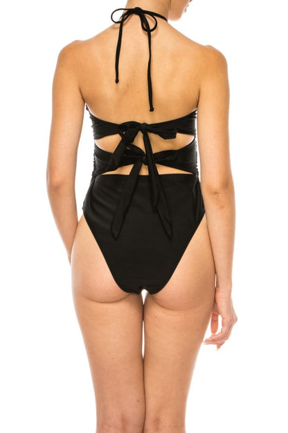 Back view of Mermaid Swimwear Floral Wrap black swimsuit with tie-back design on model