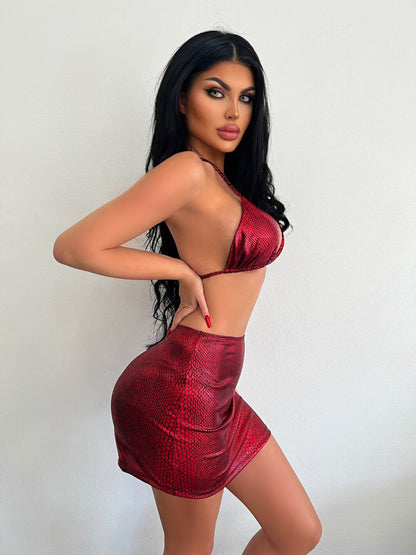 Woman modeling a red metallic three-piece bikini swimsuit with a shiny high-waisted skirt and halter top