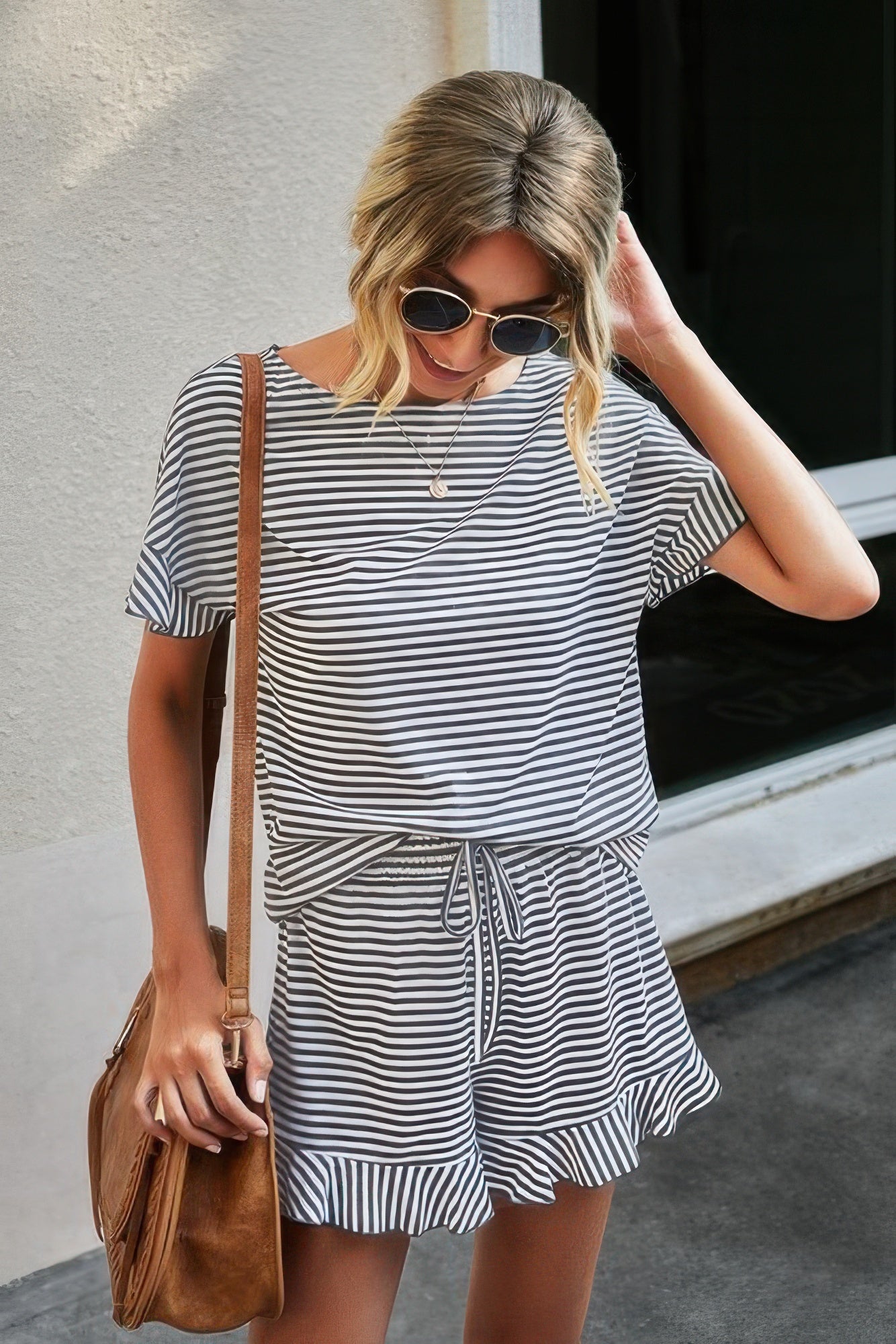 CCWHOLESALECLOTHING model wearing a black and white striped short set for women with tie waist shorts and crossbody bag
