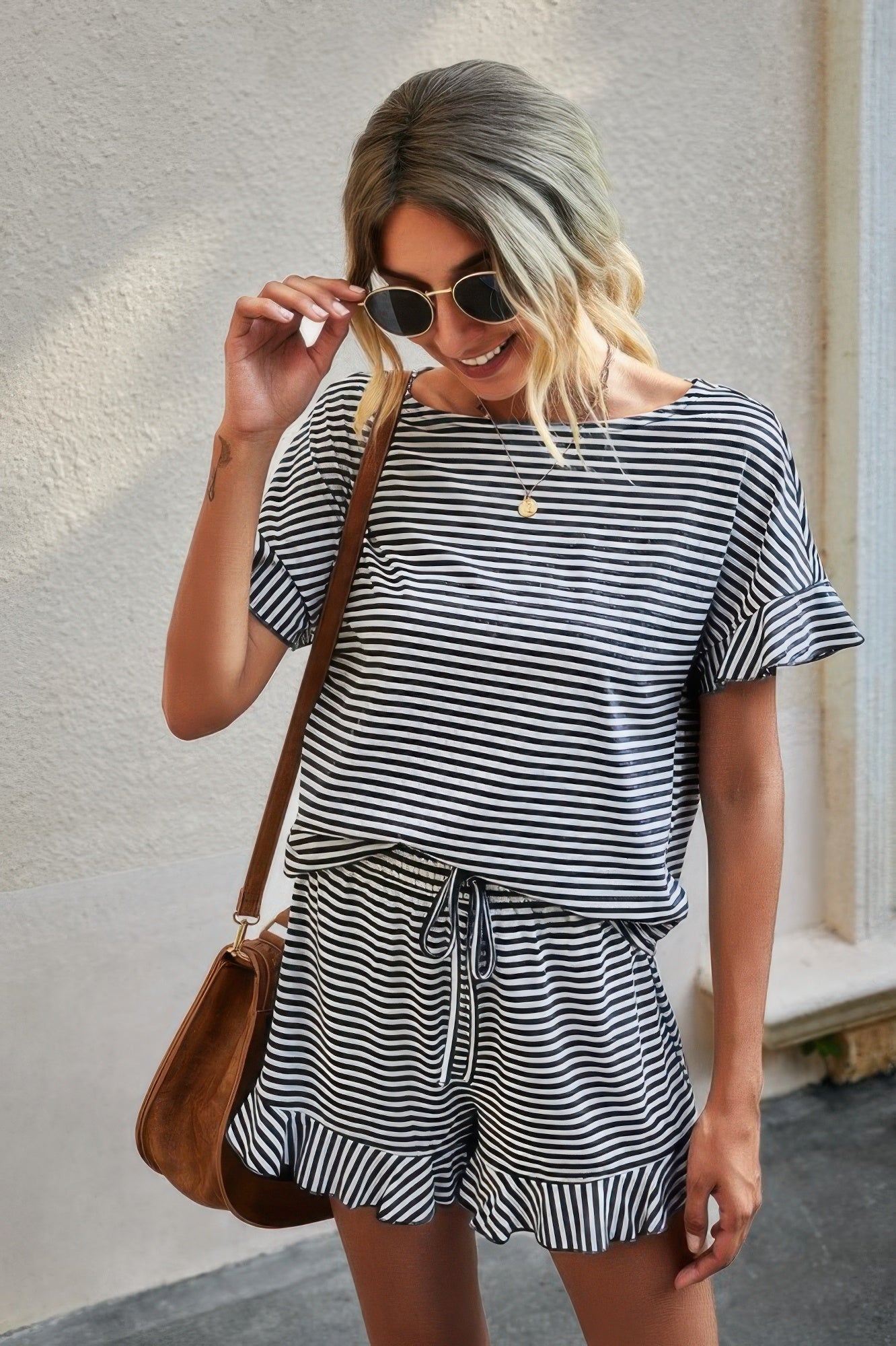 Woman wearing a black and white striped short set for women with ruffle sleeves and drawstring shorts