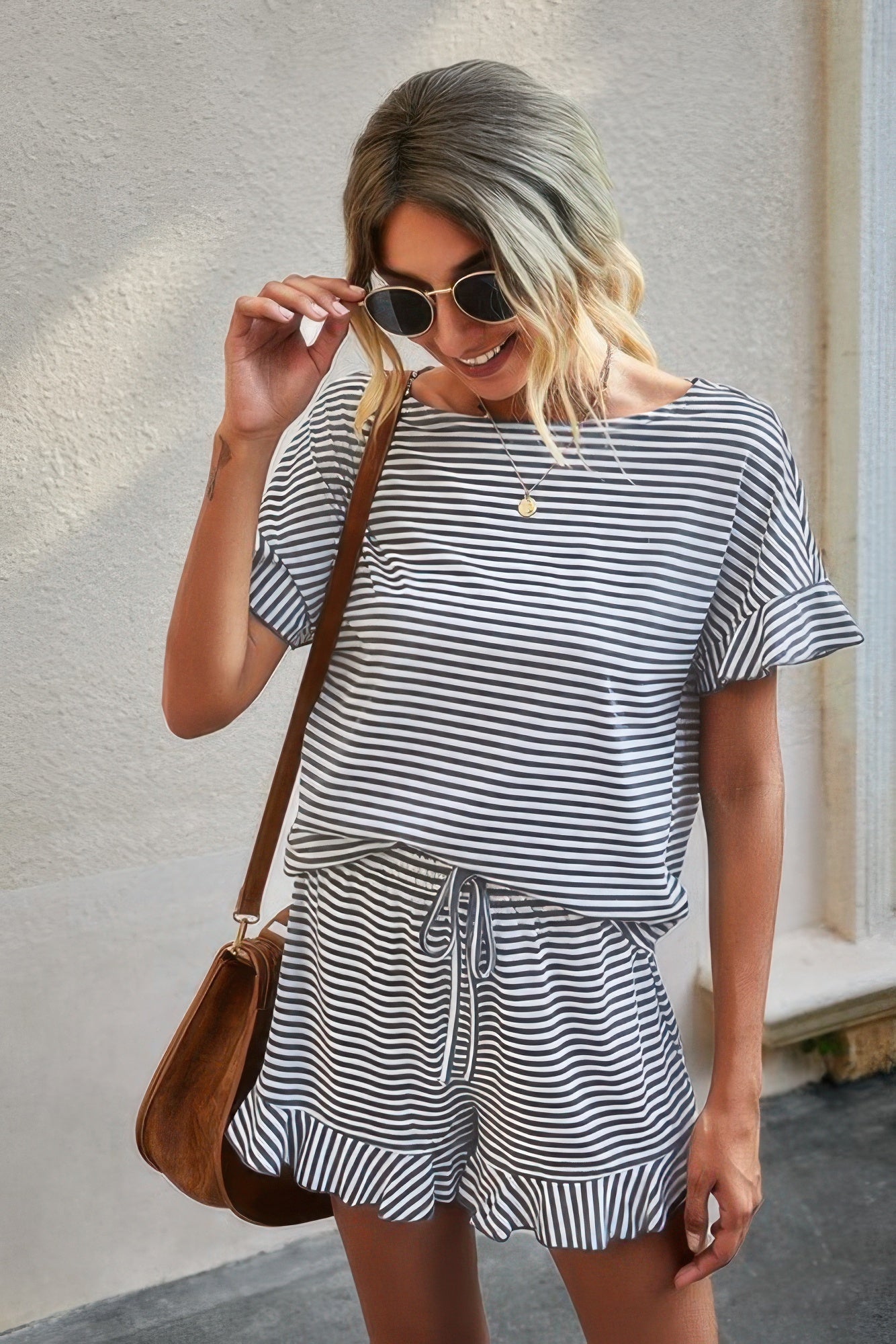Woman wearing black and white striped short set for women with ruffle sleeves and drawstring ruffle hem shorts and brown bag