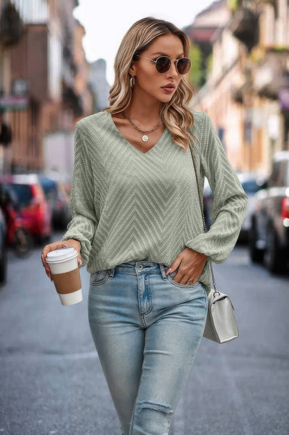 Woman wearing sage green V neck Long Sleeve Loose Top with light wash jeans holding coffee cup