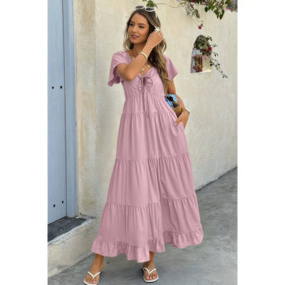 Woman in dusty pink square neck ruffle hem dress, tiered maxi, flutter sleeves, sandals and sunglasses