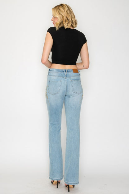 Artemis Vintage model wearing women's high rise embroidered bootcut jeans in light wash back view with floral embroidery
