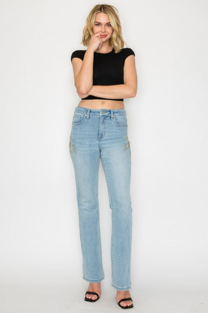 Artemis Vintage model wearing women's high rise embroidered bootcut jeans light wash with floral side embroidery