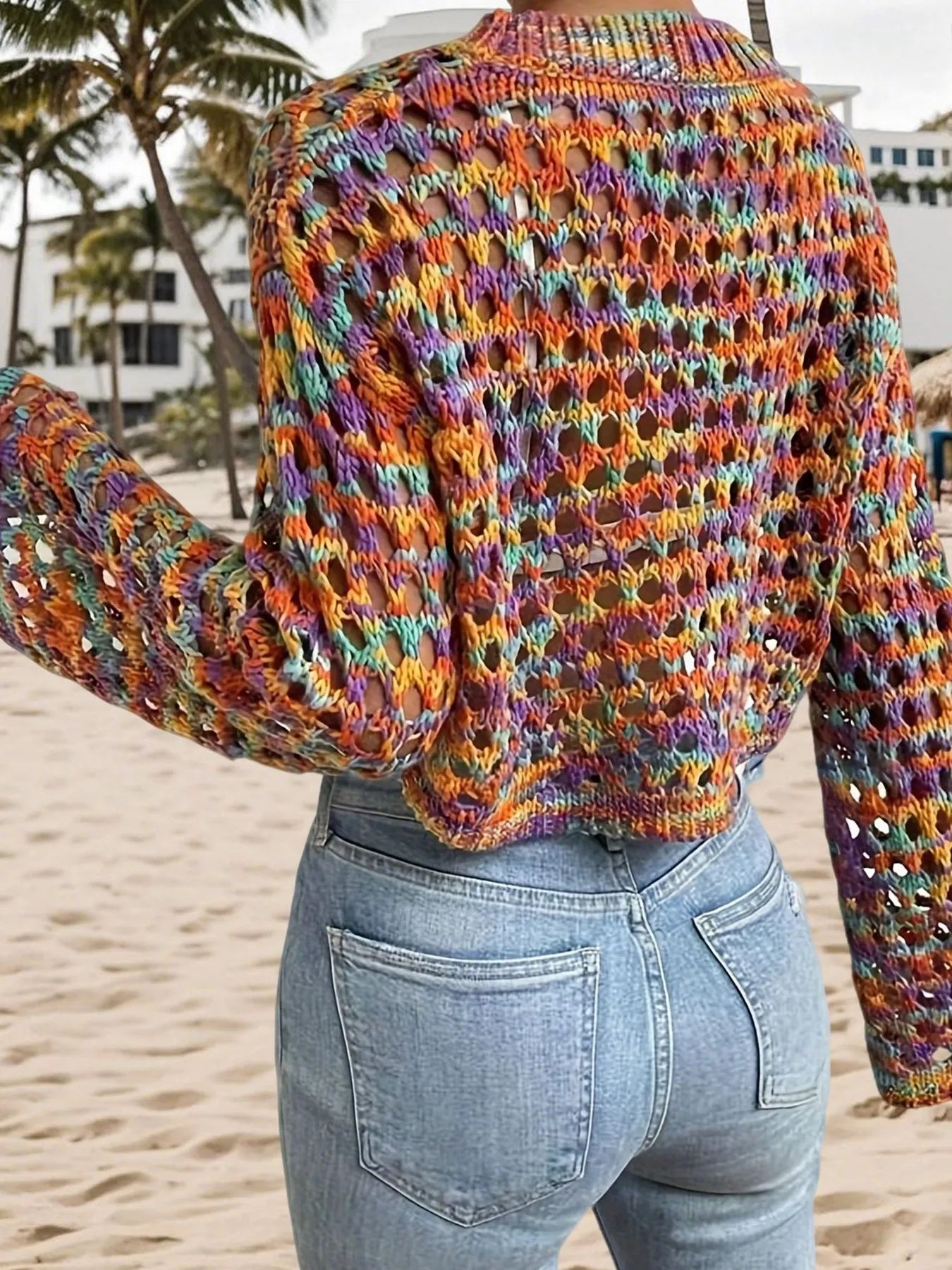 Trendsi Hollow Out Cropped Sweater multicolor open knit back view styled with high waisted jeans on beach