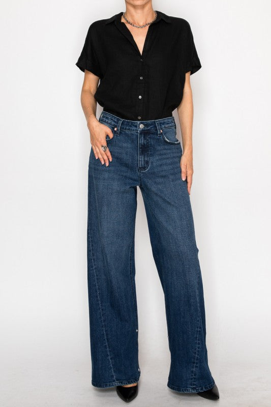 Artemis Vintage model wearing dark wash high rise wide leg jeans for women with black short sleeve button shirt