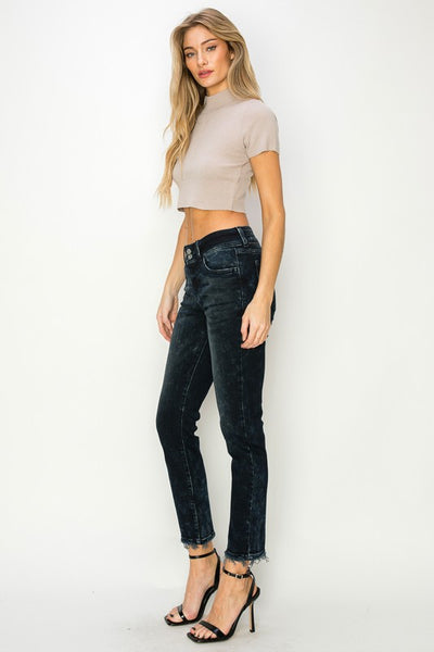 Artemis Vintage model wearing women's mid rise cigarette jeans in black washed denim with raw hem and slim fit