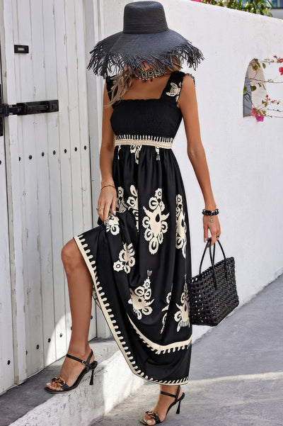 Woman wearing black sleeveless square neck dress with cream floral print smocked bodice and side slit floppy hat and woven handbag