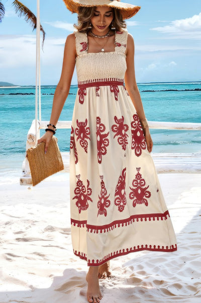 Woman on beach wearing sleeveless square neck dress cream maxi with red floral print smocked bodice and straw hat