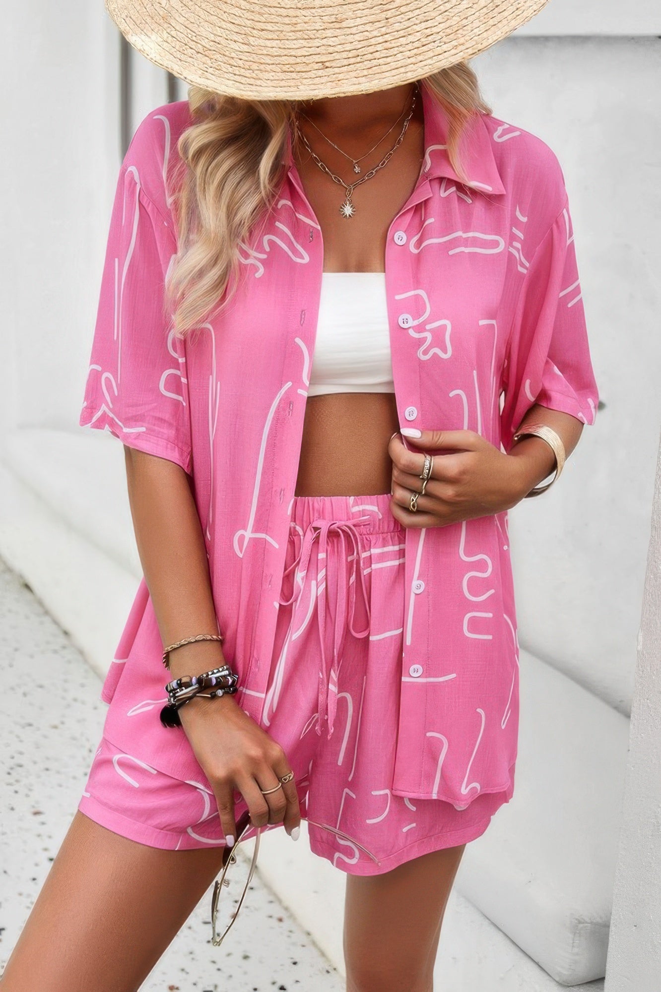 Model wearing CCWHOLESALECLOTHING pink two piece shorts set with open button shirt and drawstring waist shorts