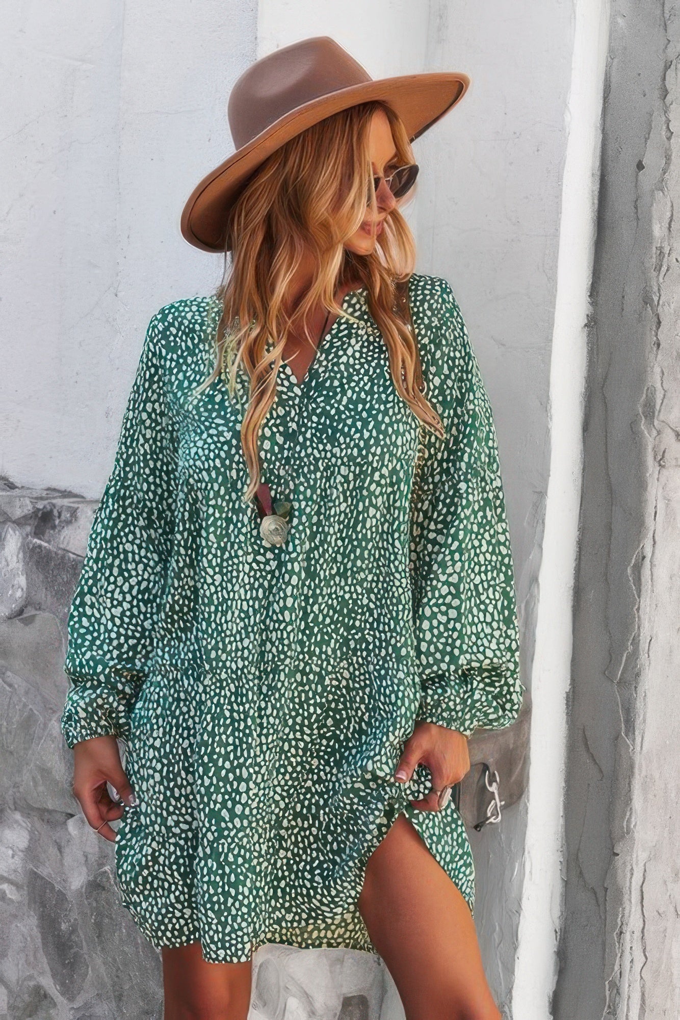 Model wearing a green v neck polka dot tunic dress with long sleeves hat and sunglasses casual summer look
