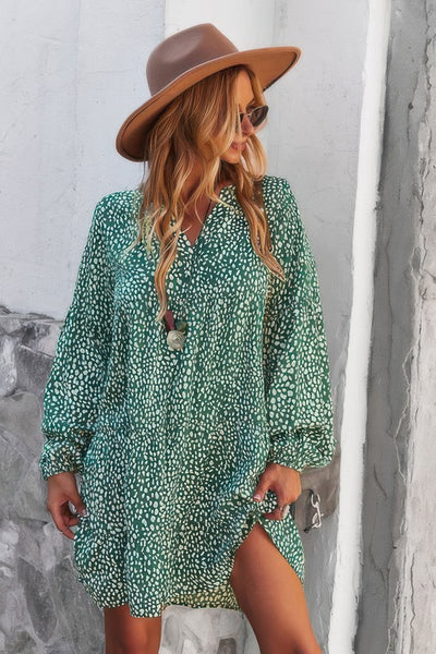 Model wearing a green v neck polka dot tunic dress with long sleeves hat and sunglasses casual summer look