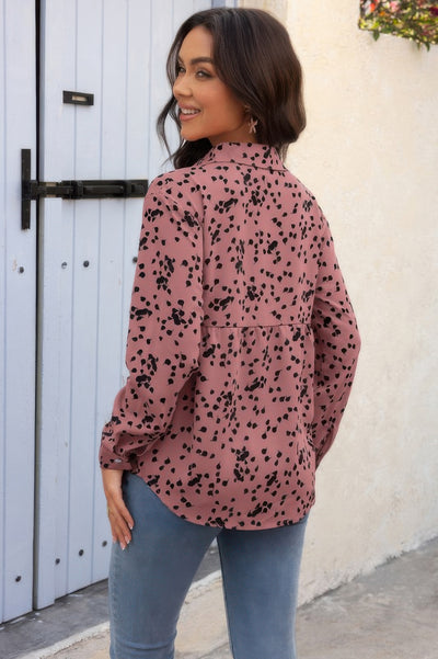 Woman smiling over shoulder wearing a pink spotted Button Down Loose Blouse with jeans outdoors