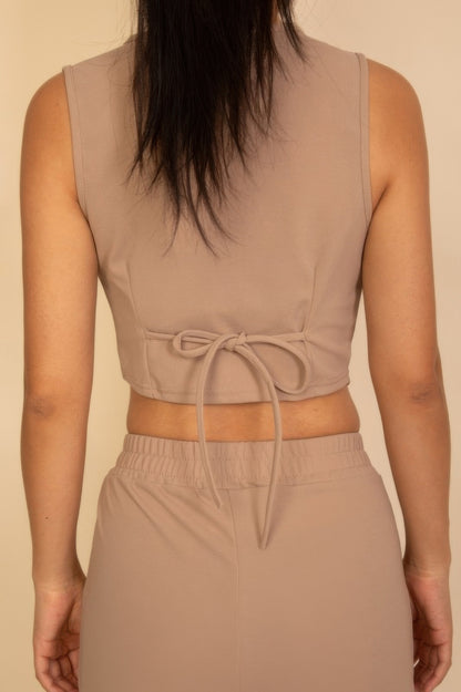 Back view of a tailored button vest in beige with a tie closure for a stylish fit