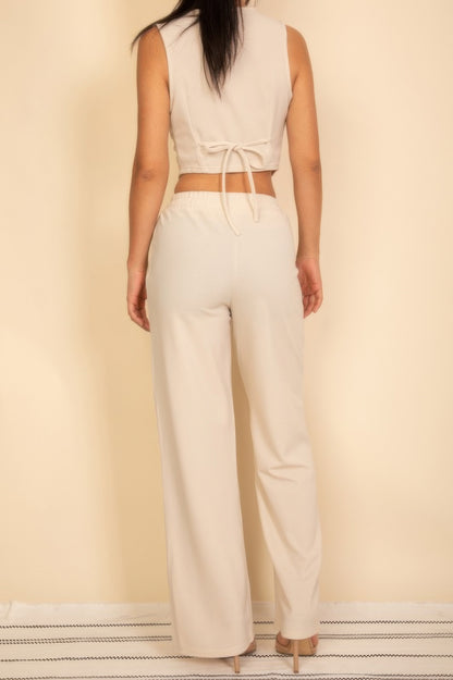 Back view of a woman wearing a light beige tailored button vest paired with matching pants.