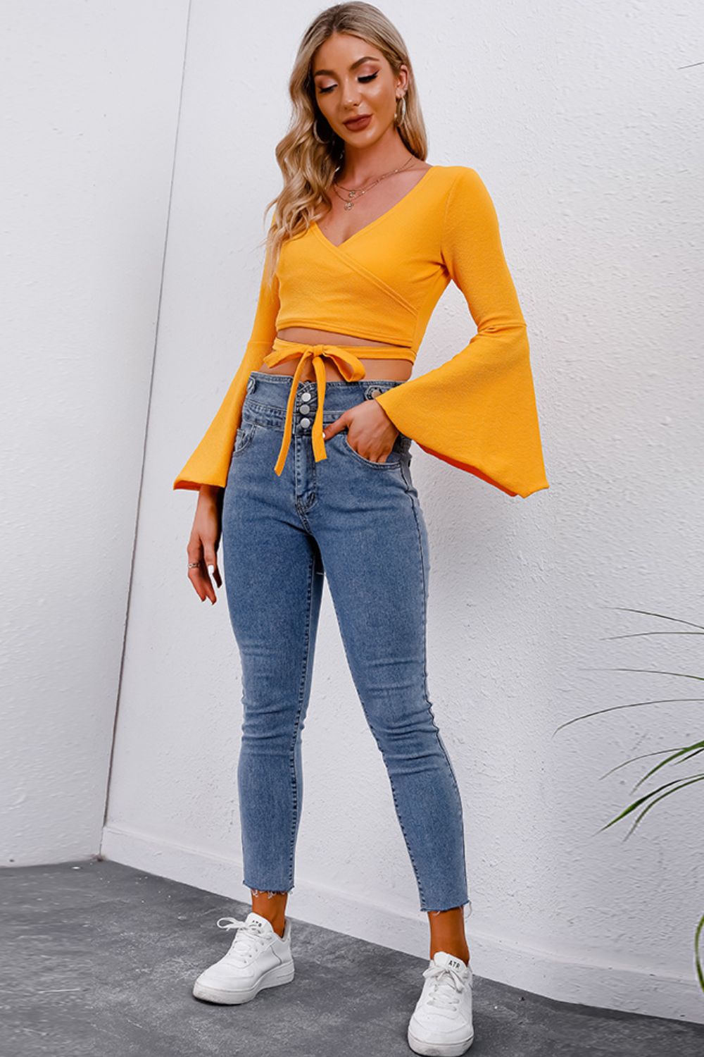 Trendsi Tie Front Cropped Top in vibrant yellow with bell sleeves, paired with high-waisted jeans