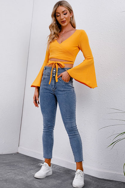 Trendsi Tie Front Cropped Top in vibrant yellow with bell sleeves, paired with high-waisted jeans