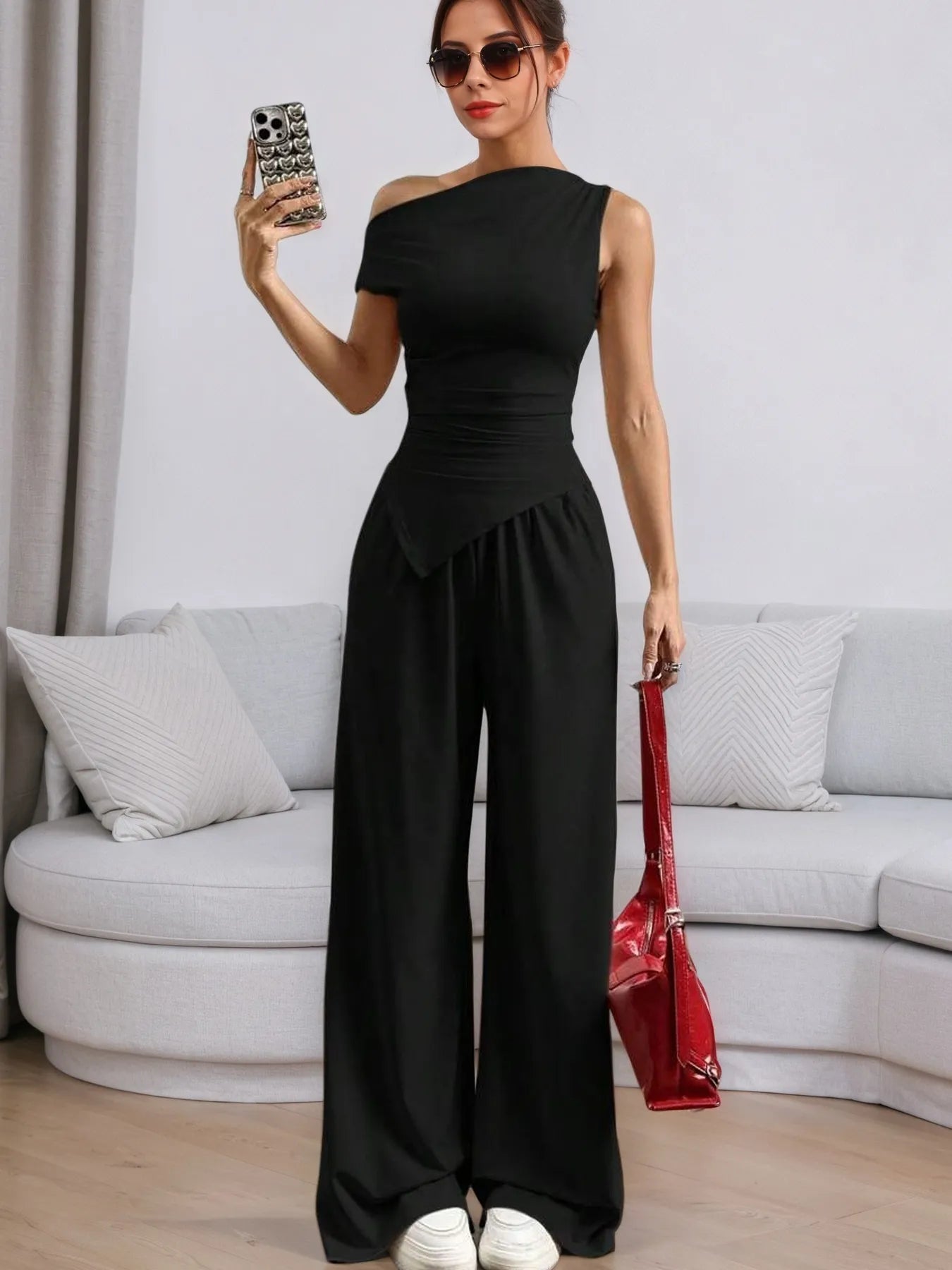 Stylish woman in a black jumpsuit with Trendy Pants, posing confidently in a modern living room