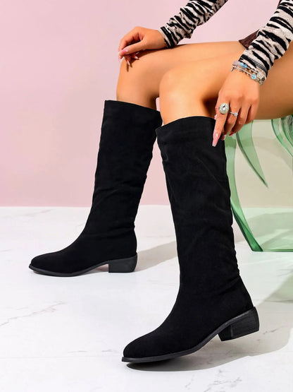 Trendsi Suede Knee-High Boots in black with low block heel shown on a seated model