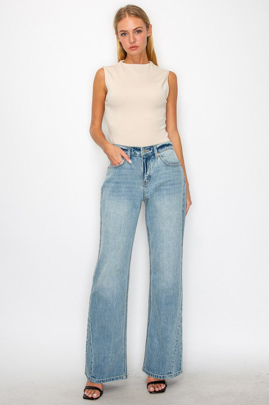 Artemis Vintage women's mid rise flare jeans light wash on model wearing beige sleeveless top and sandals