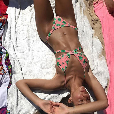 Woman wearing a Tropical Print Brazilian Cut Bikini lying on a white towel at the beach